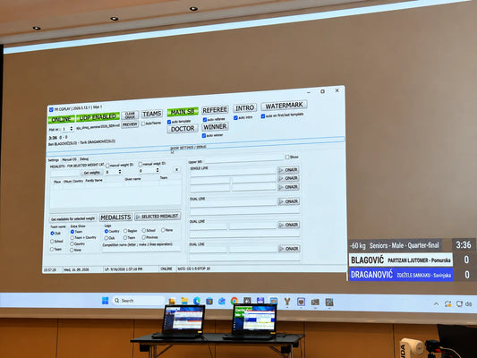 Projected computer interface beside a small Judo scoreboard, with two laptops on a table below.